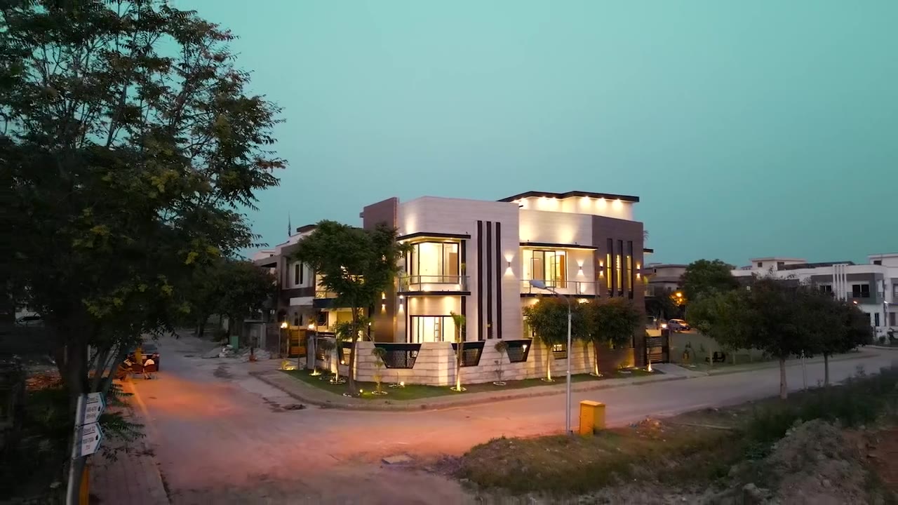 Casa Línea corner house at dusk with pale stone, black fins and illuminated windows