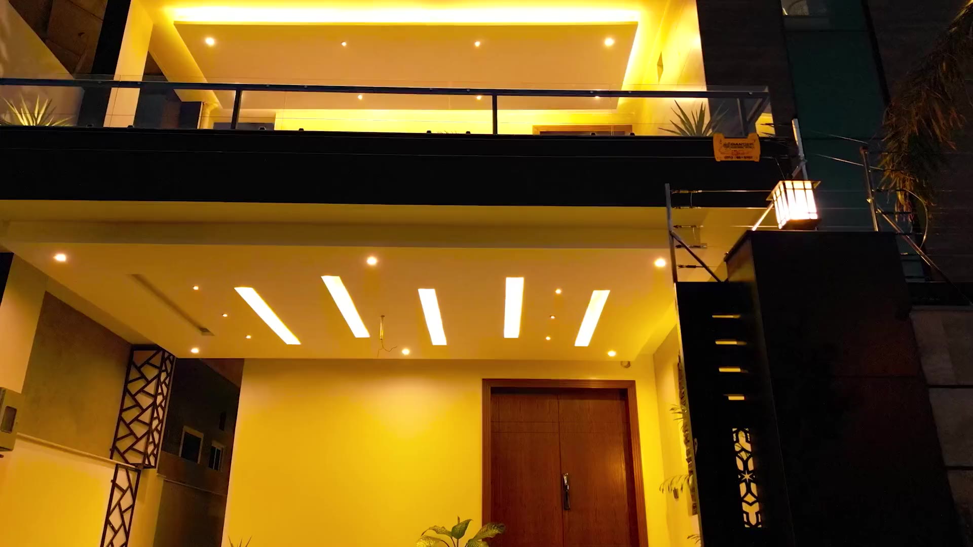 The lit entrance canopy and timber front door at dusk