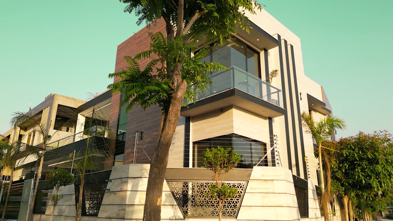 The angled corner bay with its glass balcony, framed by a tree